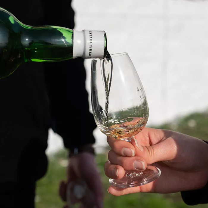 Laphroaig scotch whisky being poured into a glass outdoors